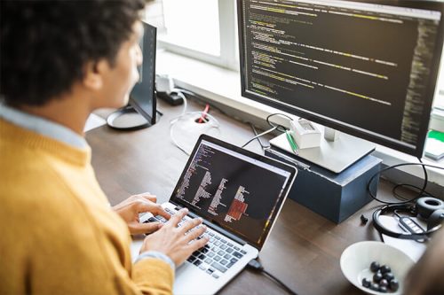 person using laptop and second monitor screen