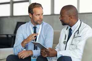 healthcare administrator speaking with doctor in medical office.