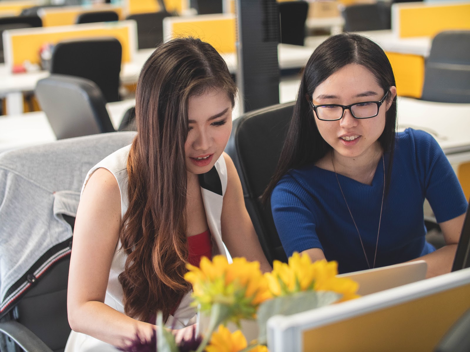 shallow focus photography of two women doing work at a table