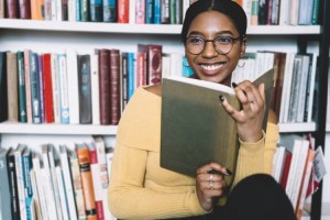 A smiling editor consults a book in her office.