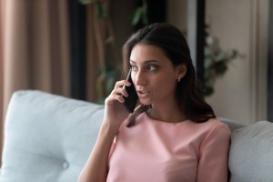 a woman holding cell phone to her ear and speaking