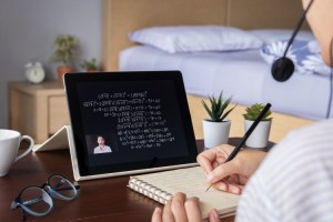 A student watches an online algebra tutorial on a tablet.