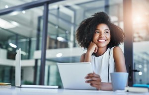 A smiling person works at a laptop.