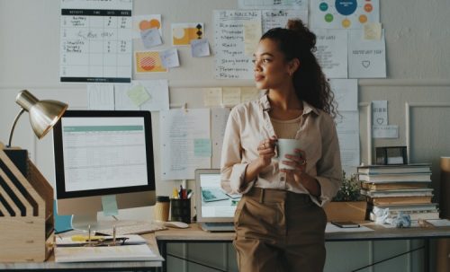 A professional holds a coffee mug in a quiet office.