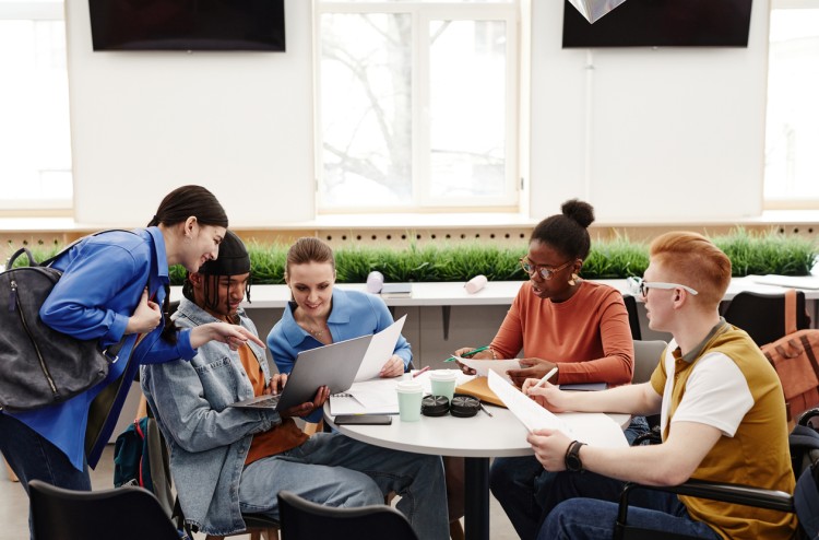 A diverse group of college students studying together around a table.