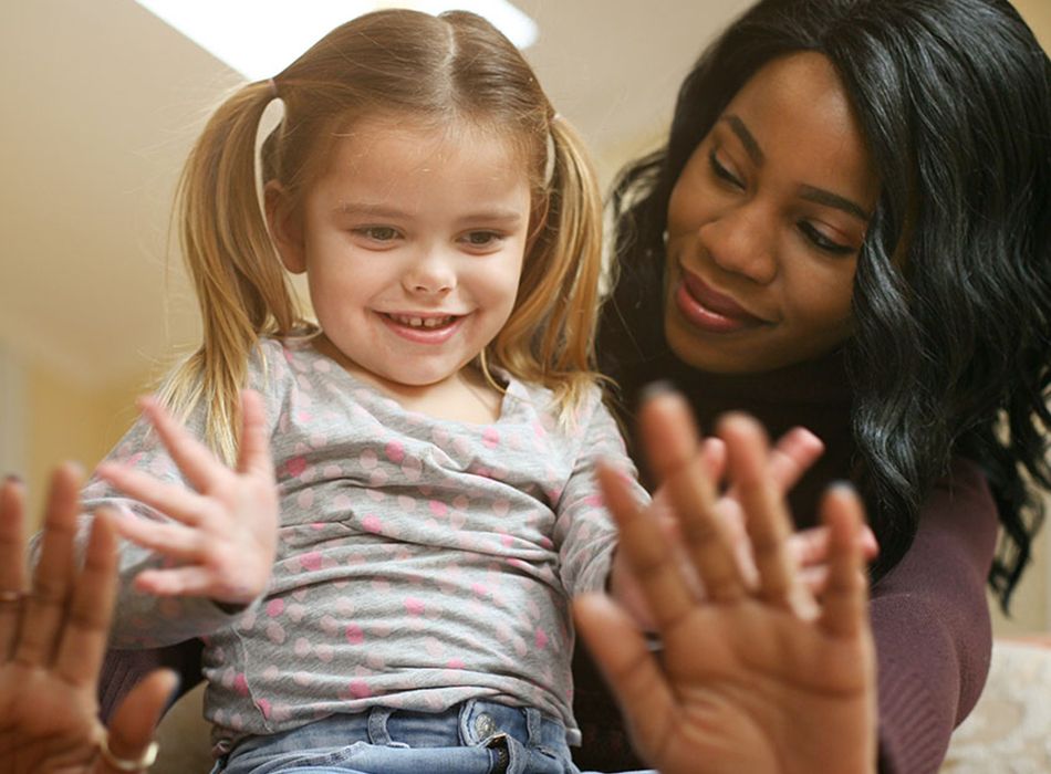 A woman and a little girl with their hands outstretched, embodying themes of Human Development and Family Studies.