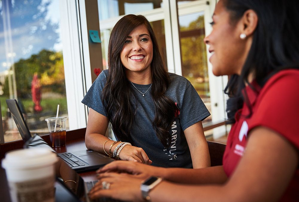 Undergraduate students sitting with laptops having a discussion