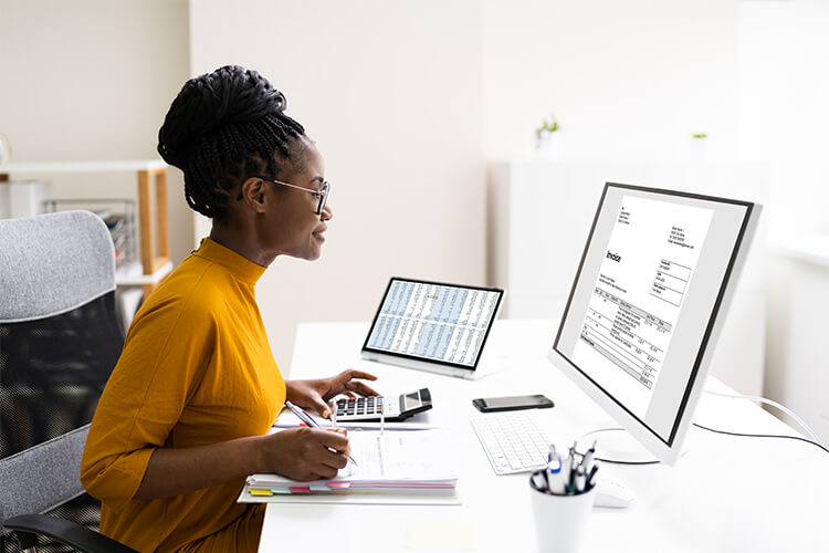 a managerial accountant reviews sits at desk to review an invoice