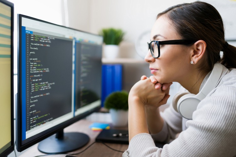 A software developer looks at code on a computer screen.