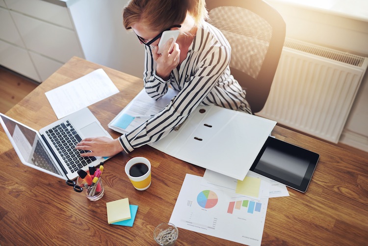 businesswoman on the phone while working on her laptop at her desk