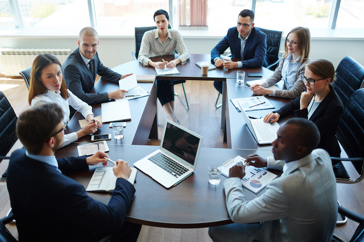 A group of businesspeople meet around a boardroom table.