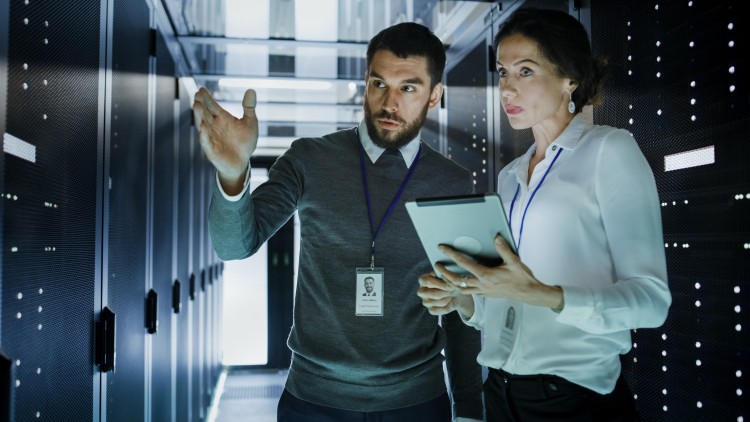 Computer and information systems manager speaking with a colleague in an information center.