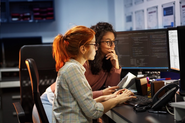 big data engineers at a desk analyzing a computer screen