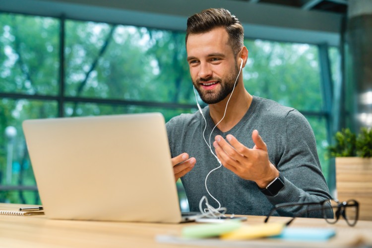 A ghostwriter wearing headphones has an online conversation with a client. 