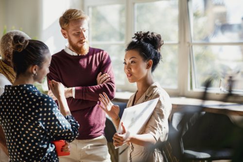 A corporate communications manager meets with team members in the office.