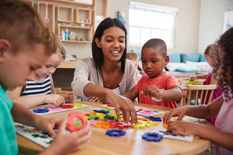 A preschool director leads young students in an activity