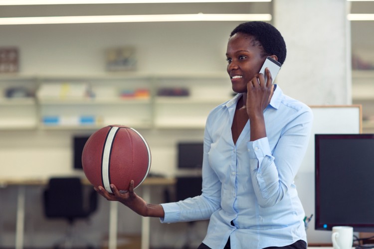 A sports manager holding a ball talks on the phone.