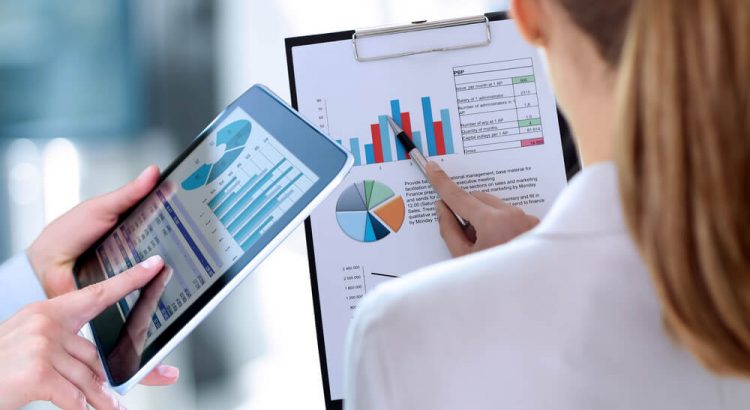 business colleagues working and analyzing financial figures on both a tablet and clipboard