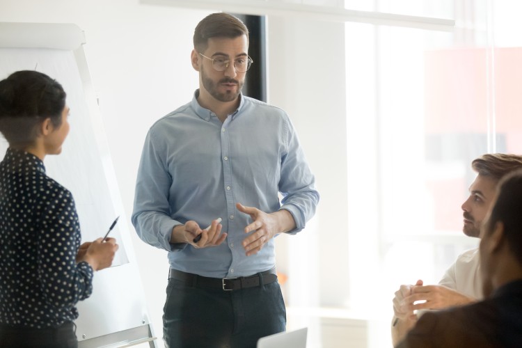 A wellness manager is standing and speaking to a group in a well-lit conference room.