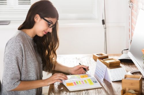 A student writes a schedule in a planner.