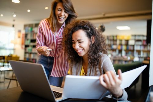 Two people laughing during a study break in a library.